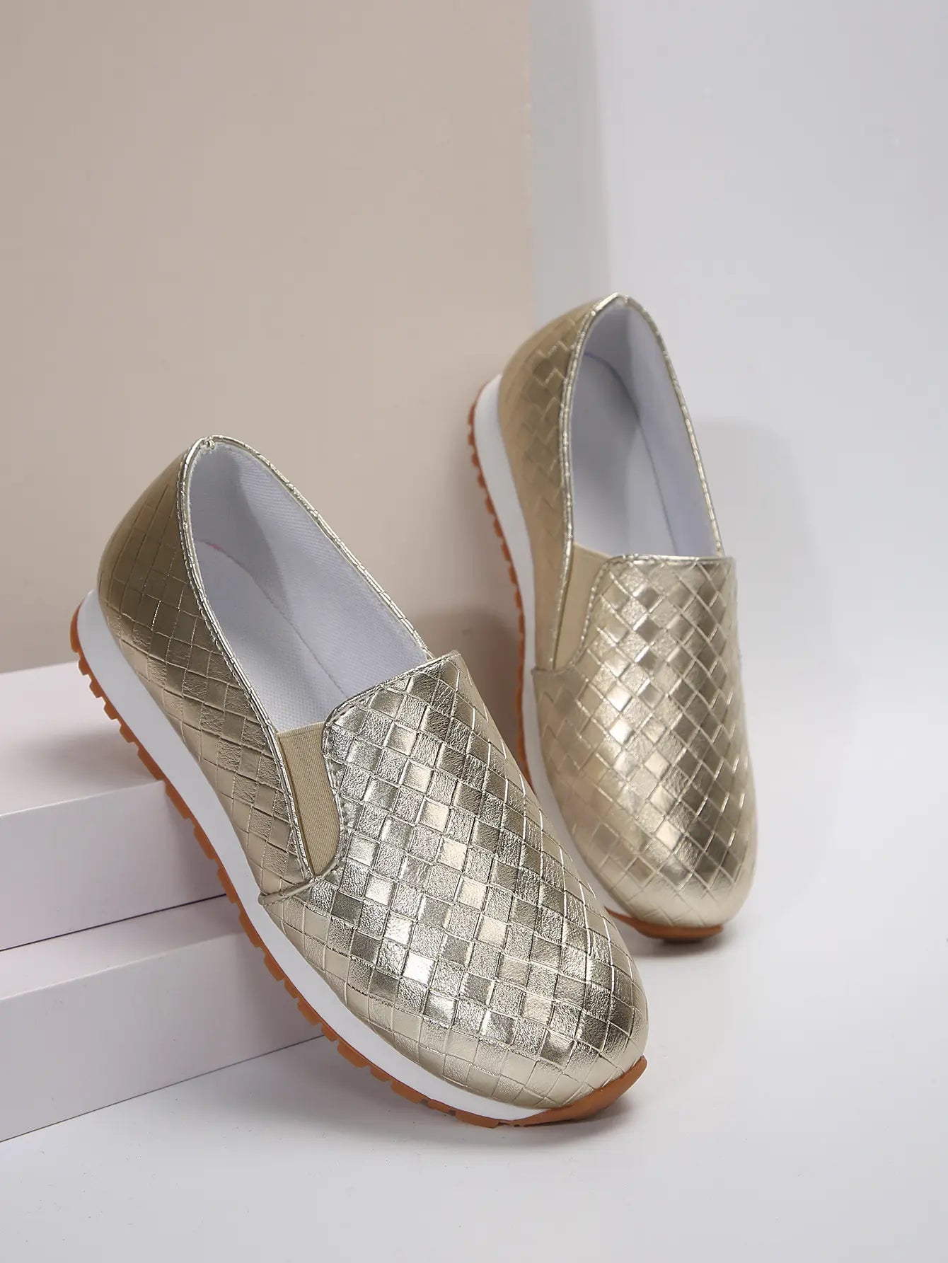 Zymir women's metallic gold slip-on loafers featuring a distinctive woven upper texture and a comfortable flat rubber sole, shown from a three-quarter angle.