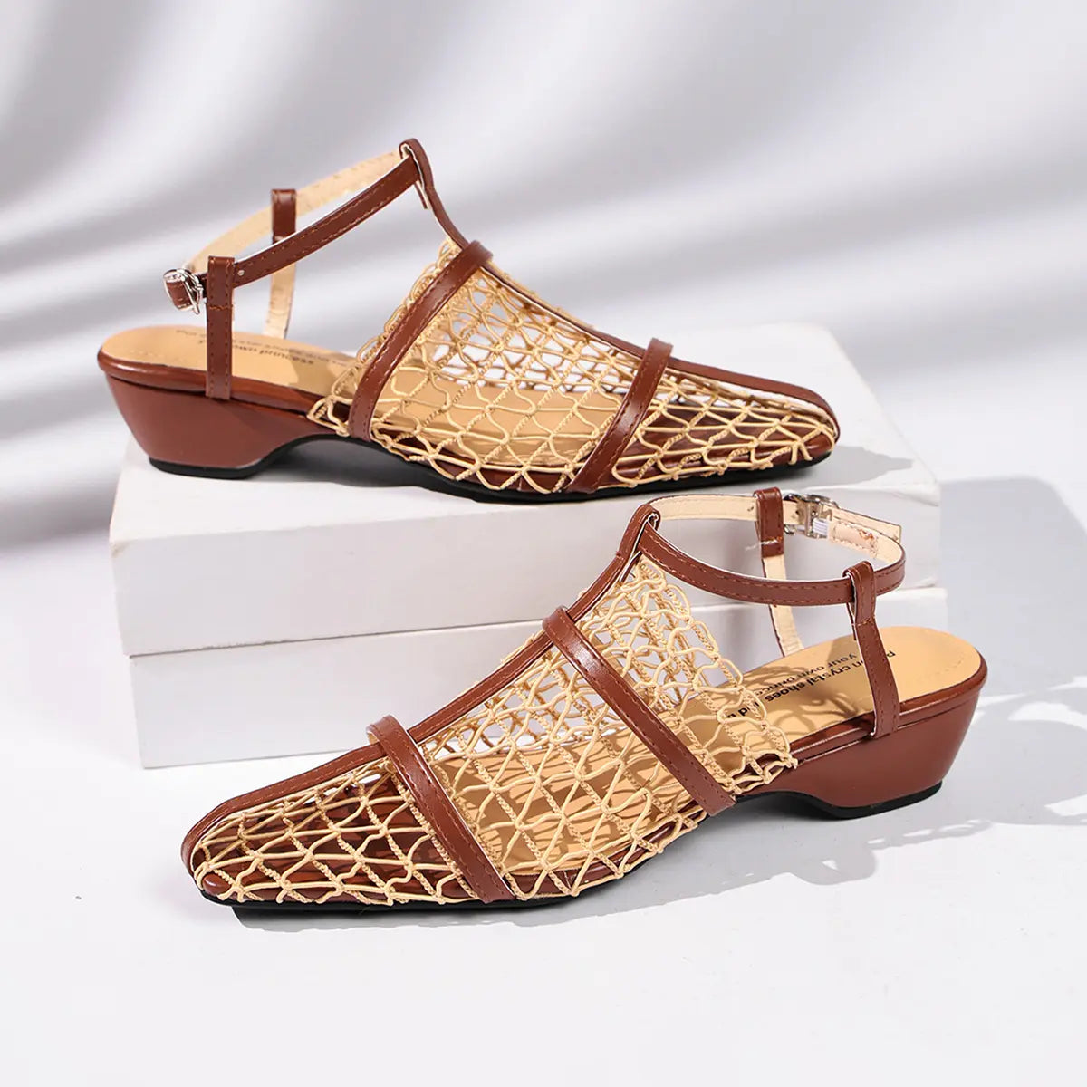 A pair of Zynthis woven mesh heeled sandals in brown and natural, featuring a pointed toe, low block heel, and adjustable ankle strap. Shown from a three-quarter angle on a studio background.