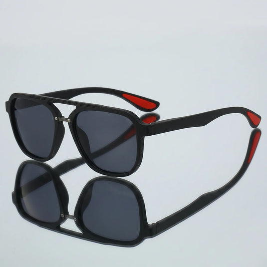 Matte black aviator sunglasses with a double bridge and dark mirrored lenses, featuring a visible red accent on the temple tips. Presented in a three-quarter view.