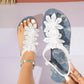 White bohemian thong sandals with delicate floral lace embellishments and elasticated ankle straps, shown on a foot with a turquoise beaded anklet.