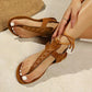 Zyra bohemian flat sandals in deep brown suede-like material, featuring decorative cross-stitching on the toe strap and adjustable braided ankle ties, shown on a model's feet.