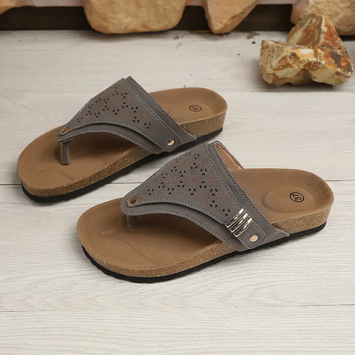 Grey suede-like PU thong sandals with intricate laser-cut geometric patterns and gold-tone buckle details, featuring a cork-patterned footbed and platform rubber sole.