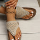 Zyra laser-cut platform thong sandals in a light neutral color, shown on a model's feet with white nail polish and a gold ankle bracelet.