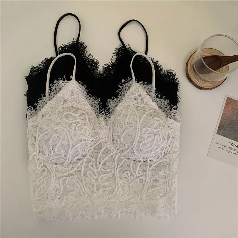 Two Zyrin Romantic Lace Cropped Camisoles, one white and one black, displayed flat-lay. Both camisoles feature intricate floral lace with eyelash trim along the v-neck and scalloped hem, and delicate spaghetti straps.